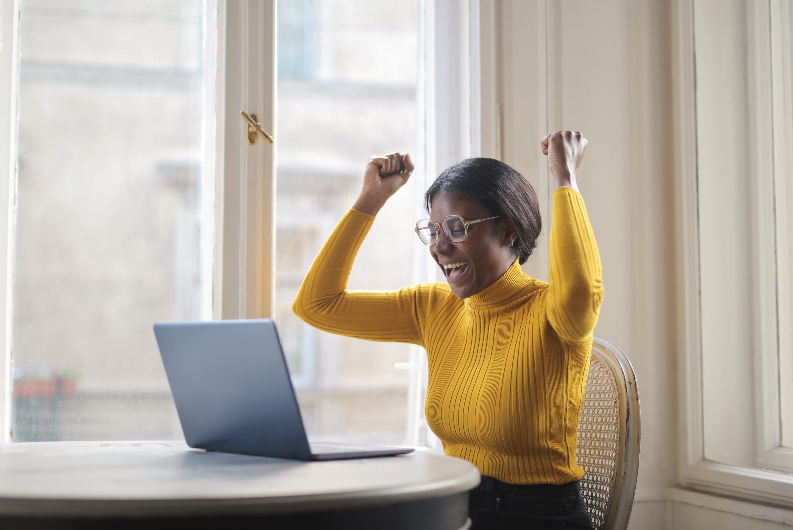 black woman rejoices in front of a computer